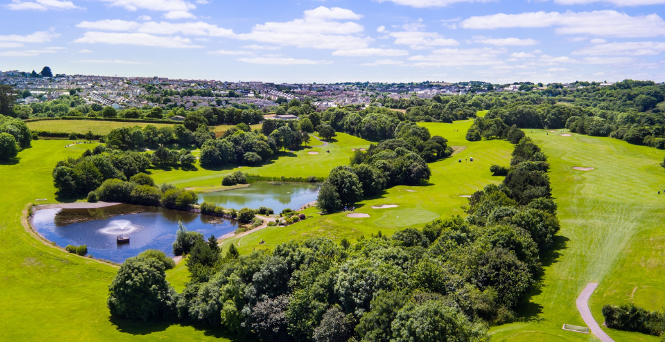 An aerial view of China Fleet Golf Club. Green grass and golf holes with a fountain in the middle